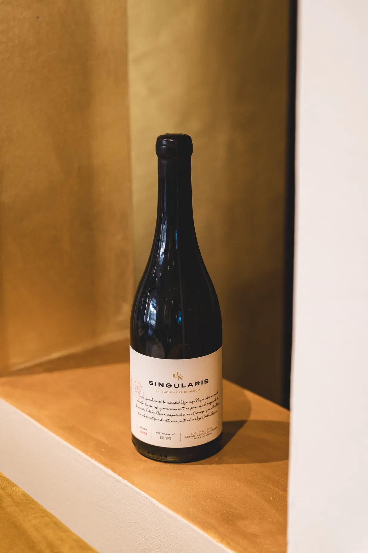 Botella de vino Singularis sobre una repisa de madera